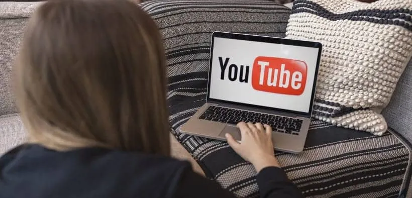 Vrouw achter laptop waarop groot YouTube staat