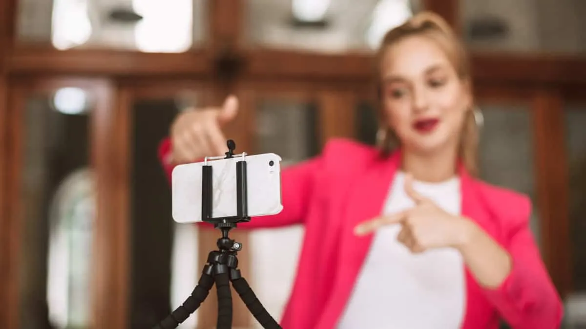 Vrouw voor mobiele camera neemt pose aankom sociale media video’s te verbeteren