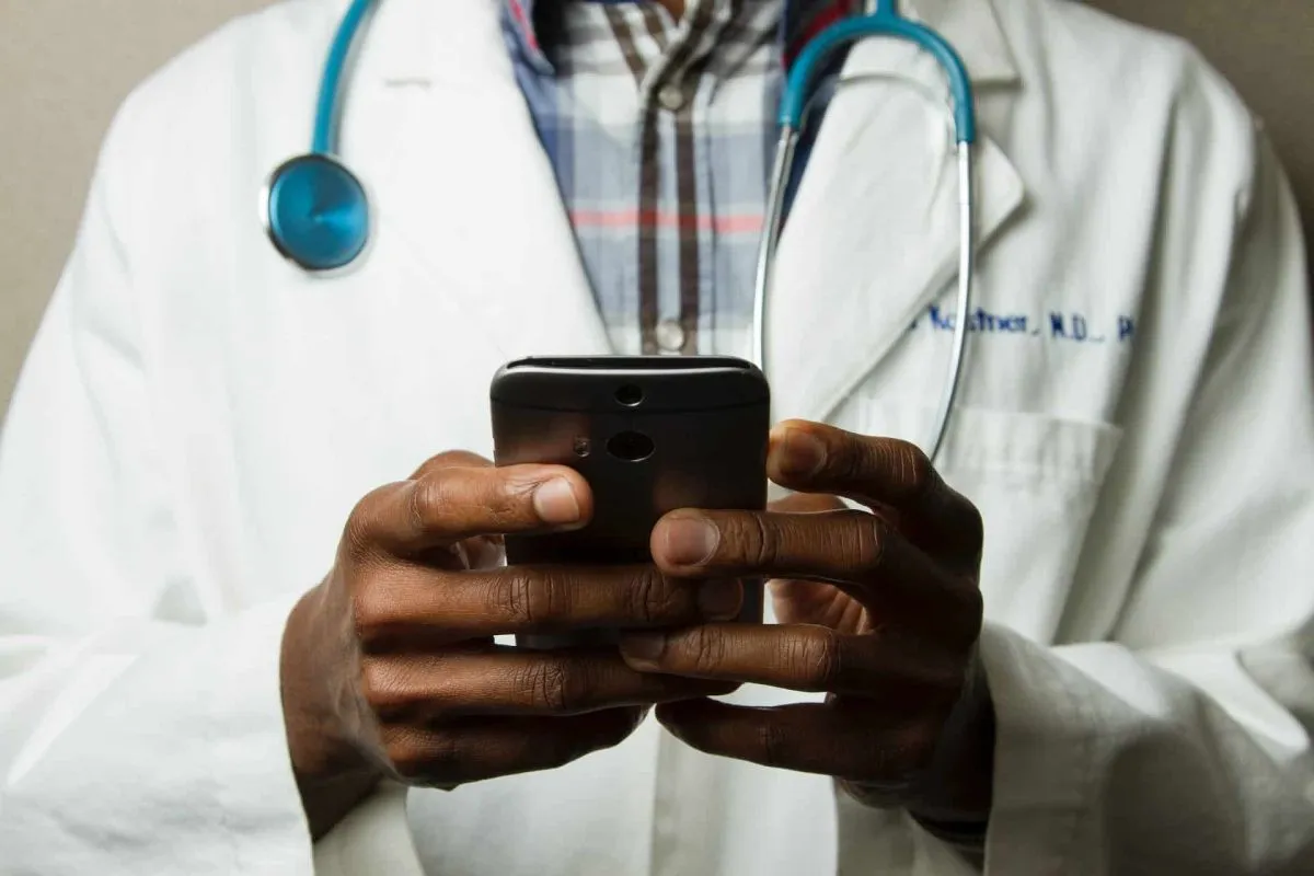 Man met doktersjas en stethoscoop om zijn nek zit op mijn mobieltje