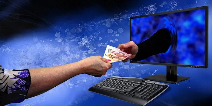 Een computerscherm waaruit geld wordt aangepakt vanuit de hand van de computeraar 
