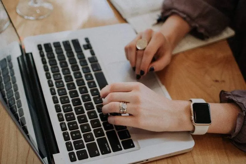 Handen van vrouw met horloge om die liggen op het toetsenbord van een MacBook. Cookies intrekken